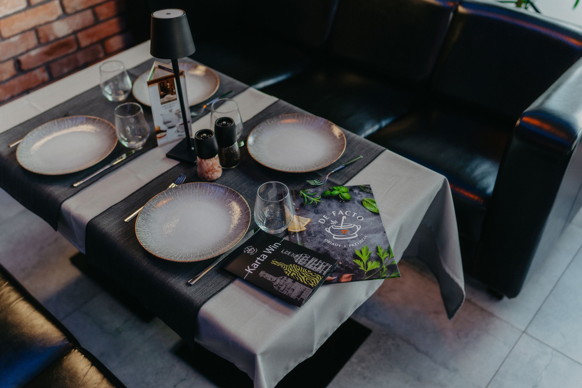 Nakryty stolik w restauracji De Facto z kartą dań i kartą win
